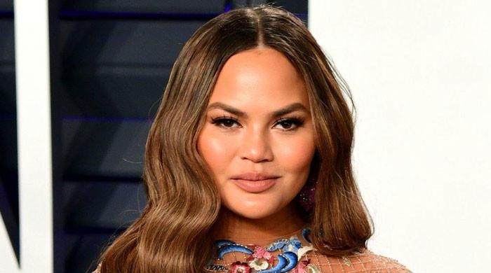 Chrissy Teigen takes on banker role 18 years after briefcase model debut